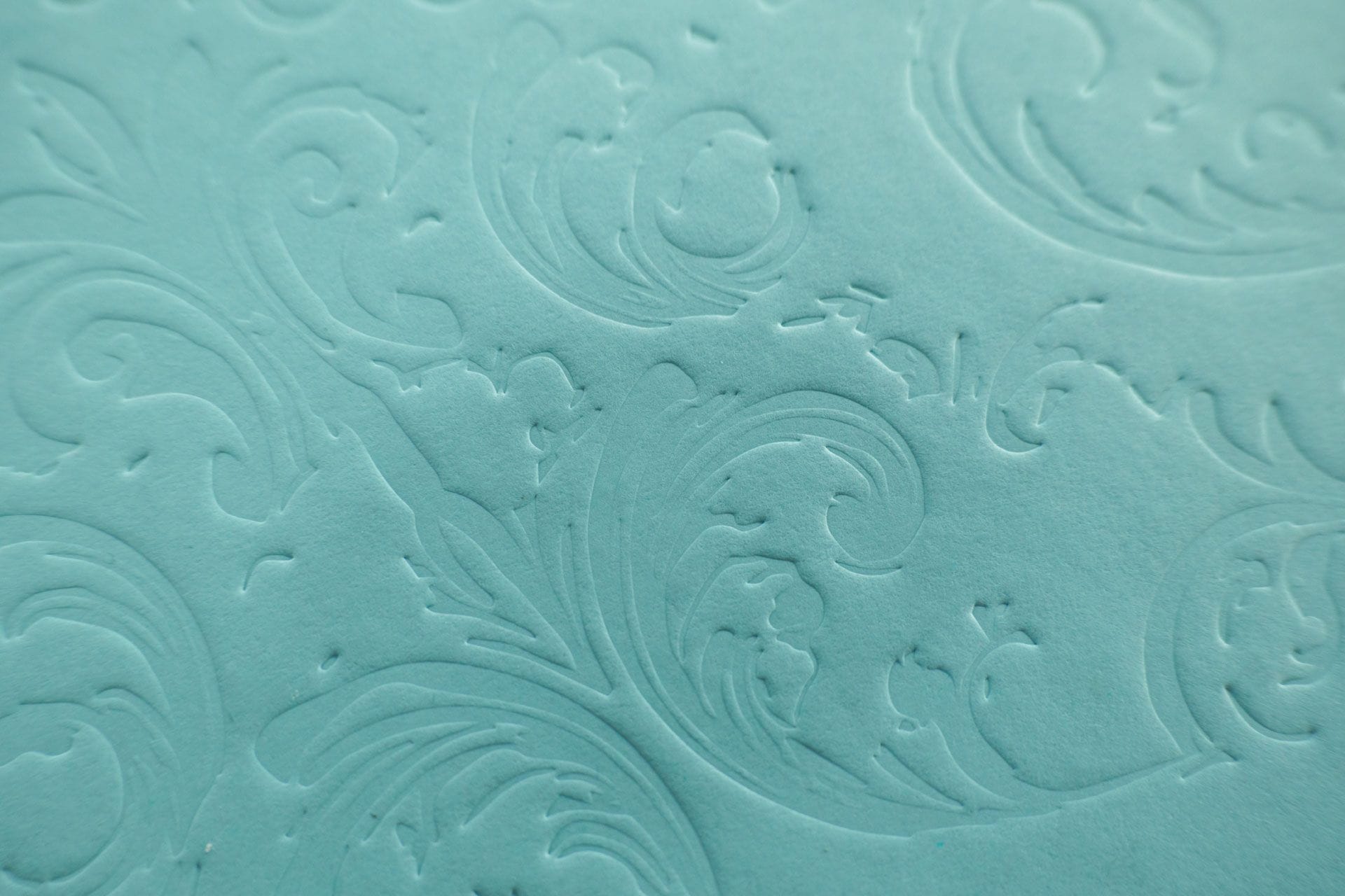 The cover of The Hidden Thread in turquoise paper with a debossed baroque ornament