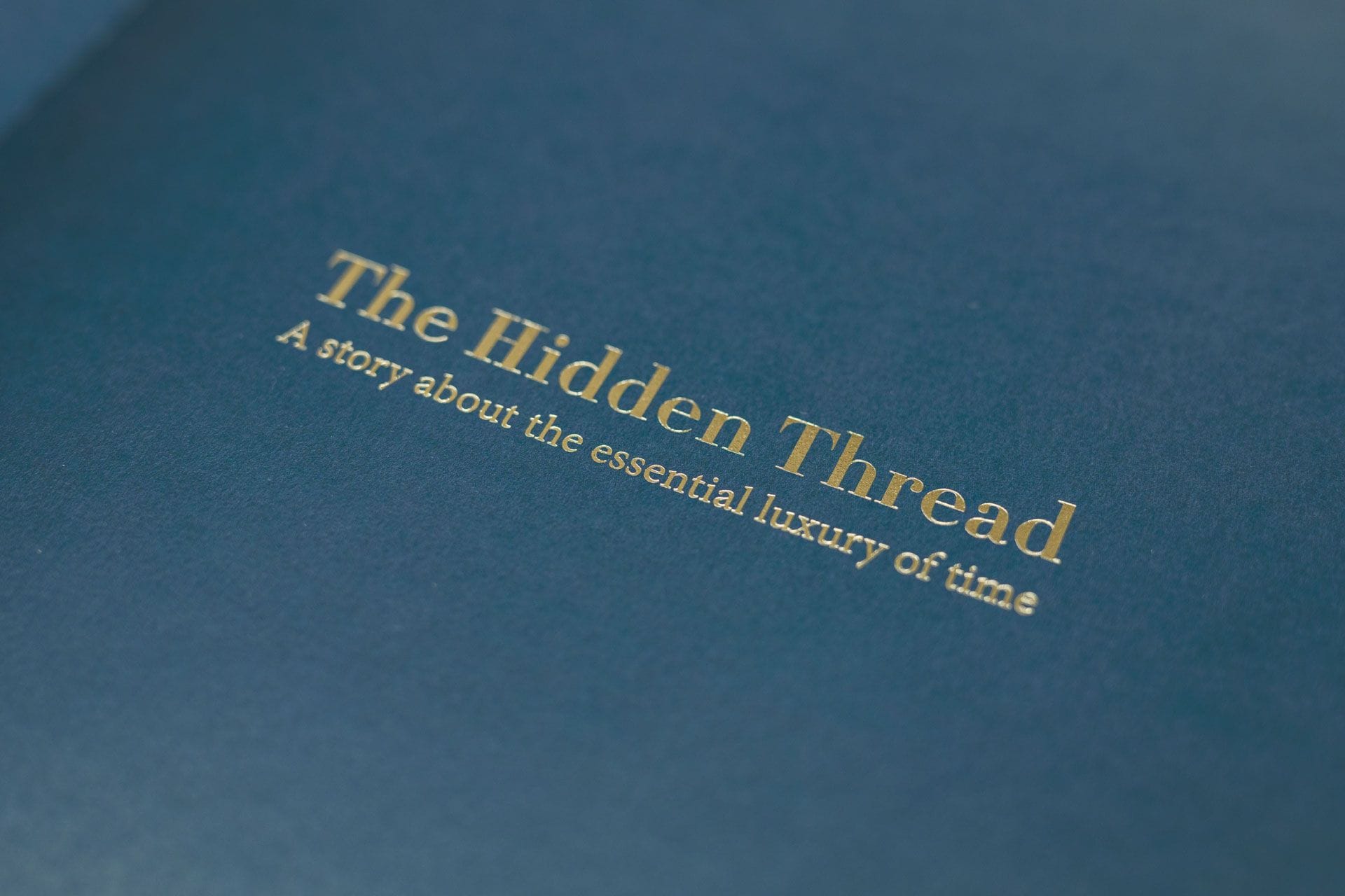 The title page of The Hidden Thread, gold foil lettering on deep blue paper